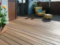 Drewniany taras z żółtym fotelem i pufą. Idealne miejsce do relaksu, gdy zastanawiasz się, czym wyłożyć taras tanio.