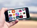 Dłoń trzyma telefon z ikonami aplikacji do edycji zdjęć na Androida.