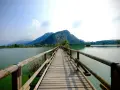 Ponte in legno su lago calmo, montagne verdi sullo sfondo. Un luogo incantevole per scoprire cosa vedere in Franciacorta, tra natura e tranquillità.