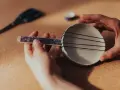 Dłonie tworzą domowy instrument strunowy, pokazując, jakie są instrumenty szarpane.