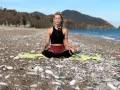 Frau in Meditation am Strand, tiefe Konzentration auf die Wellen.