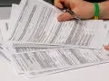 Dłoń z długopisem nad stosem dokumentów podatkowych PIT.
