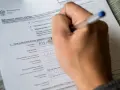 Ręka wypełnia formularz "Zgłoszenie pobytu stałego". Czy jest obowiązek meldunku? Tak, ten dokument to potwierdza.
