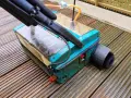 Gerät zur Bankirai Terrasse reinigen mit Bürstenaufsatz auf nassen Holzbrettern.
