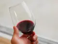 Dłoń trzyma kieliszek czerwonego wina. Czy wino jest zdrowe? To pytanie nurtuje wielu miłośników tego trunku.