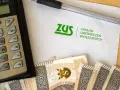 Kalkulator, długopis, banknoty i dokument ZUS. To ZUS wypłaca L4 ciążowe.