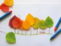 Bunte Herbstblätter werden zu Bäumen arrangiert. Ein kleiner Fuchs schaut neugierig hervor. Perfekt für Herbst basteln Kinder!