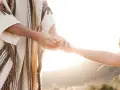 A person in a robe holds another's hand, symbolizing how to surrender to God through trust and guidance.