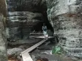 Spacerka po skalnych labiryntach Gór Stołowych. Drewniany pomost prowadzi przez mokradła między potężnymi skałami.