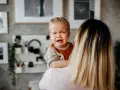 Płaczliwe dziecko nie chce się przytulać do mamy, odwraca głowę i zaciska usta.