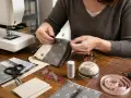 Tuto enveloppe rectangulaire : mains cousant un portefeuille en tissu, avec machine à coudre, ciseaux, épingles et ruban à mesurer.