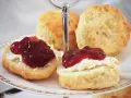 Was sind Scones? Köstliche, goldbraune Scones, bestrichen mit Clotted Cream und Marmelade, auf einer Etagere serviert. Ein Genuss für jeden Teeliebhaber.