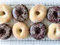Åtta hemgjorda donuts, vissa med chokladglasyr och strössel, andra med socker. Perfekt för ett donuts recept!