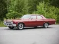 Röd Chevrolet Impala från 1965 med en tung cut, parkerad vid en skogsdunge.