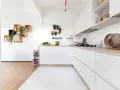 Progetto cucina angolare piccola: mobili bianchi minimalisti, piano in legno, mensole a muro con piante e vasi.