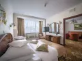 Elegancki pokój hotelowy z dużym łóżkiem, toaletką i widokiem na salon. Dowiedz się, ile kosztuje noc w hotelu Gołębiewski.