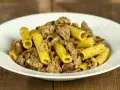 Piatto di pasta funghi e salsiccia, con rigatoni conditi con funghi trifolati e pezzetti di salsiccia saporita.