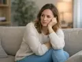 Femme assise sur un canapé, le regard perdu, pensant à quelqu'un qui n'est jamais disponible le week-end.