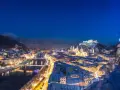 Magiczne salzburg zimą. Oświetlone miasto, rzeka Salzach i górująca twierdza Hohensalzburg w śnieżnej scenerii nocą.