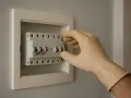 Mano con guante manipulando un magnetotérmico en un cuadro eléctrico.