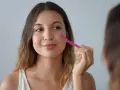 Kobieta z różową brzytwą do twarzy wykonuje zabieg depilacji.