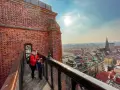 Kobieta z dzieckiem na moście pokutnic, podziwiający panoramę miasta.