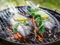 Dwie ryby na grillu, z cytryną i ziołami, unoszą się nad ogniem. Idealna jaka ryba na grilla na letni wieczór.