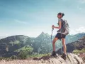 Dziewczyna z plecakiem i kijkami do trekkingu podziwia górski krajobraz. To jest właśnie hiking – przygoda na łonie natury.
