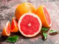 Saftige Grapefruits, frisch aufgeschnitten und als Spalten, mit grünen Blättern. Grapefruit gesund und lecker.