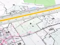 Na mapie terenowej, z naniesioną legendą MPZP, leży linijka geodezyjna.