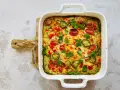 Pyszny omlet z piekarnika z pomidorkami, papryką i jalapeño, udekorowany natką pietruszki.