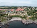 Sannes familjecamping vid kusten, med husvagnar och tält utspridda bland klippor och grönska.