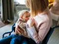 Mama w wózku inwalidzkim karmi piersią dziecko. Wkrótce nadejdzie czas, jak odstawić dziecko od karmienia piersią, ale teraz liczy się bliskość.