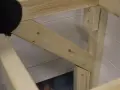En person håller på att såga snett en träbit som ska bli en del av en konstruktion.