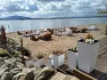 Plaża nad mietkowym zalewem z meblami z palet. W oddali góra i jezioro.