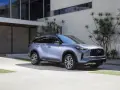 Elegancki, srebrny infiniti samochód zaparkowany przed nowoczesnym budynkiem z kamienną fasadą i dużymi oknami.