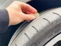Una mano tiene una moneta da 1 euro per mostrare quanti mm di battistrada ha un pneumatico nuovo. Il battistrada è usurato.
