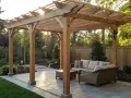 A beautiful wooden pergola, a perfect example of how to build a pergola, offers shade over a patio with outdoor furniture.