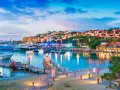 Sardynia we wrześniu: port z luksusowymi jachtami i urokliwą zabudową na wzgórzu, oświetloną ciepłym światłem.