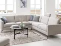 Inspiration kuddar till grå soffa: en ljusgrå hörsoffa med blå och grå mönstrade kuddar, ett runt svart soffbord med böcker och vaser, samt en randig matta.