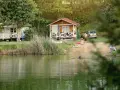 Rodzina odpoczywa nad jeziorem w malowniczym miejscu. Dzieci pluskają się w wodzie, a dorośli relaksują się na plaży przy domkach kempingowych. To idealne miejsce na rodzinne wakacje, prawdziwa **camping forteca** spokoju i radości.