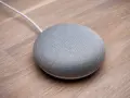 En grå Google Home Mini på ett trägolv, redo att styra ditt smarta hem med Verisure.