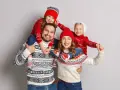 Famiglia felice con maglioni natalizi coordinati, un'ottima ispirazione per idee outfit natale.