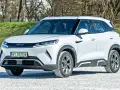 Biały SUV z logo BYD, jeden z chińskich samochodów elektrycznych, zaparkowany na żwirowej nawierzchni.