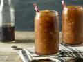 Zwei Gläser mit erfrischendem Cola Slush Eis, bereit zum Genießen. Eine Flasche Cola steht daneben.
