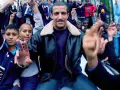 Un groupe de jeunes pose pour une photo, certains font des signes de paix. L'ambiance est celle du rap francais.
