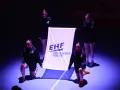 Cztery młode kobiety prezentują flagę EHF przed meczem ligi mistrzów w piłce ręcznej mężczyzn.