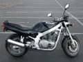 Czarny motocykl Suzuki GS 500 z chromowanym wydechem stoi na pustym parkingu.