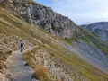 Due escursionisti percorrono un sentiero di trekking sul Gran Sasso, tra rocce e vegetazione alpina.