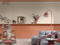 Soggiorno con pareti bicolore: la parte inferiore è color terracotta, quella superiore color crema. Arredamento moderno con divano grigio e poltrona.